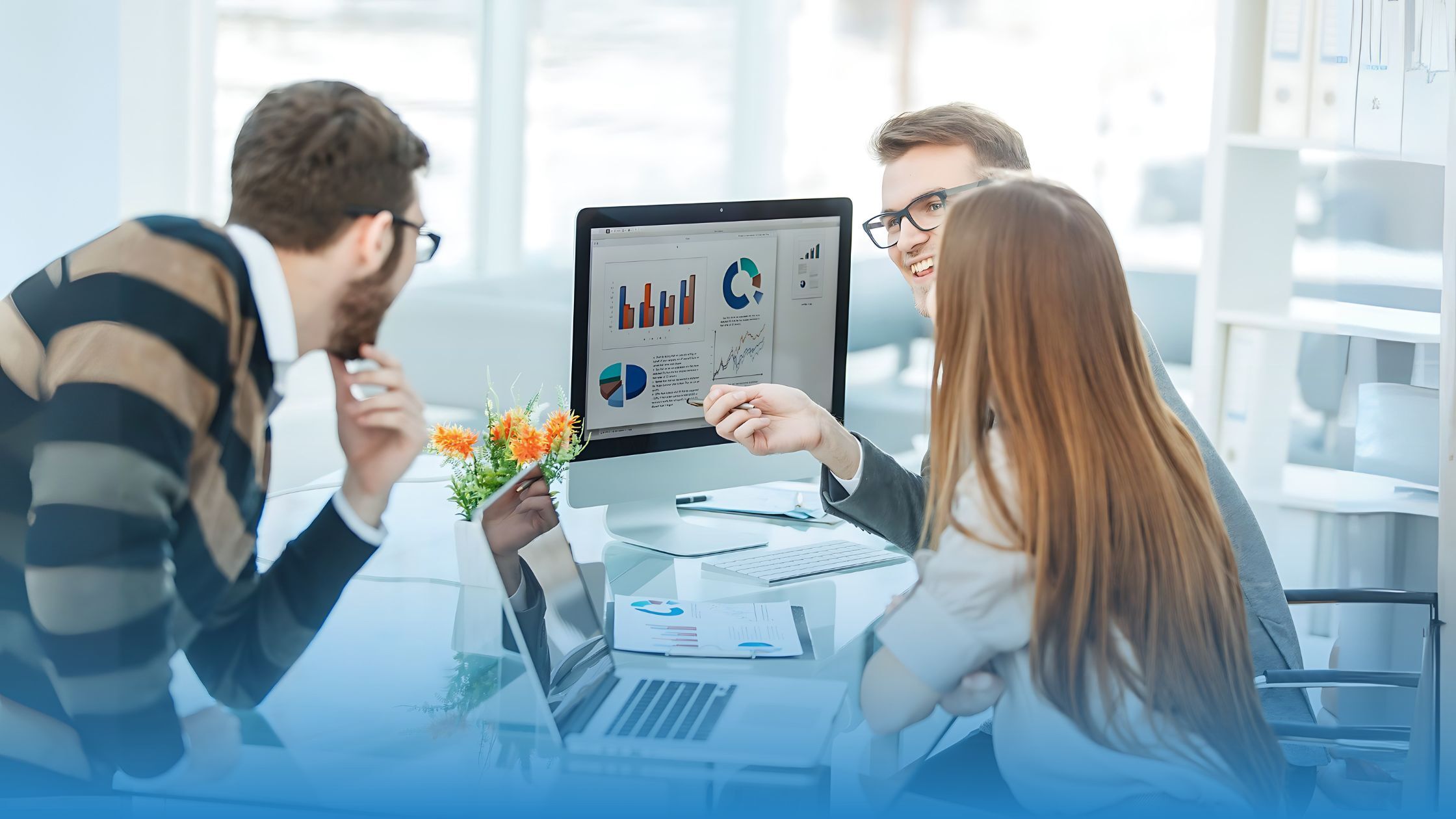 Business team in a modern office reviewing charts and analytics on a computer, representing contract benchmark analysis