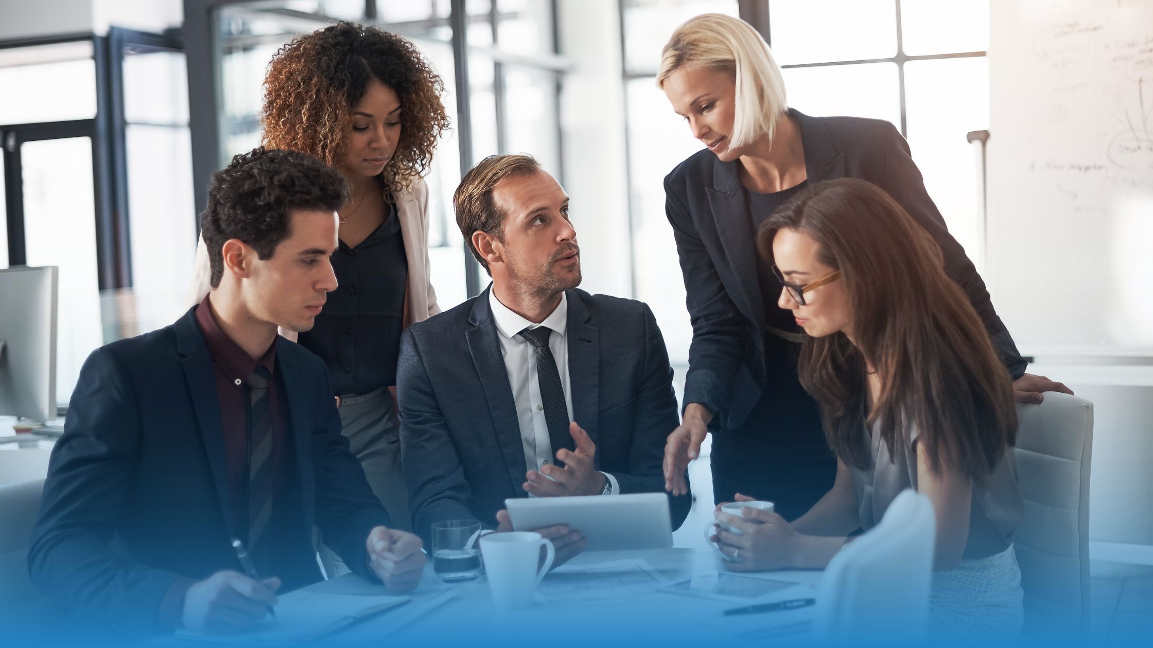 Legal and business professionals collaborating around a tablet, using machine learning tools to analyze contract terms and accelerate decision-making.