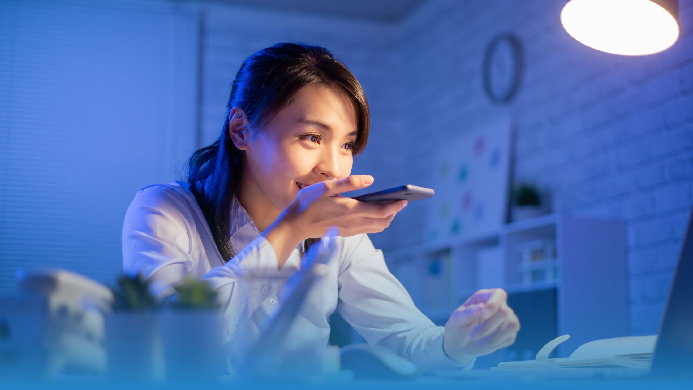 Businesswoman using voice AI technology in a modern workspace, symbolizing the integration of artificial intelligence in contract analysis and decision-making.