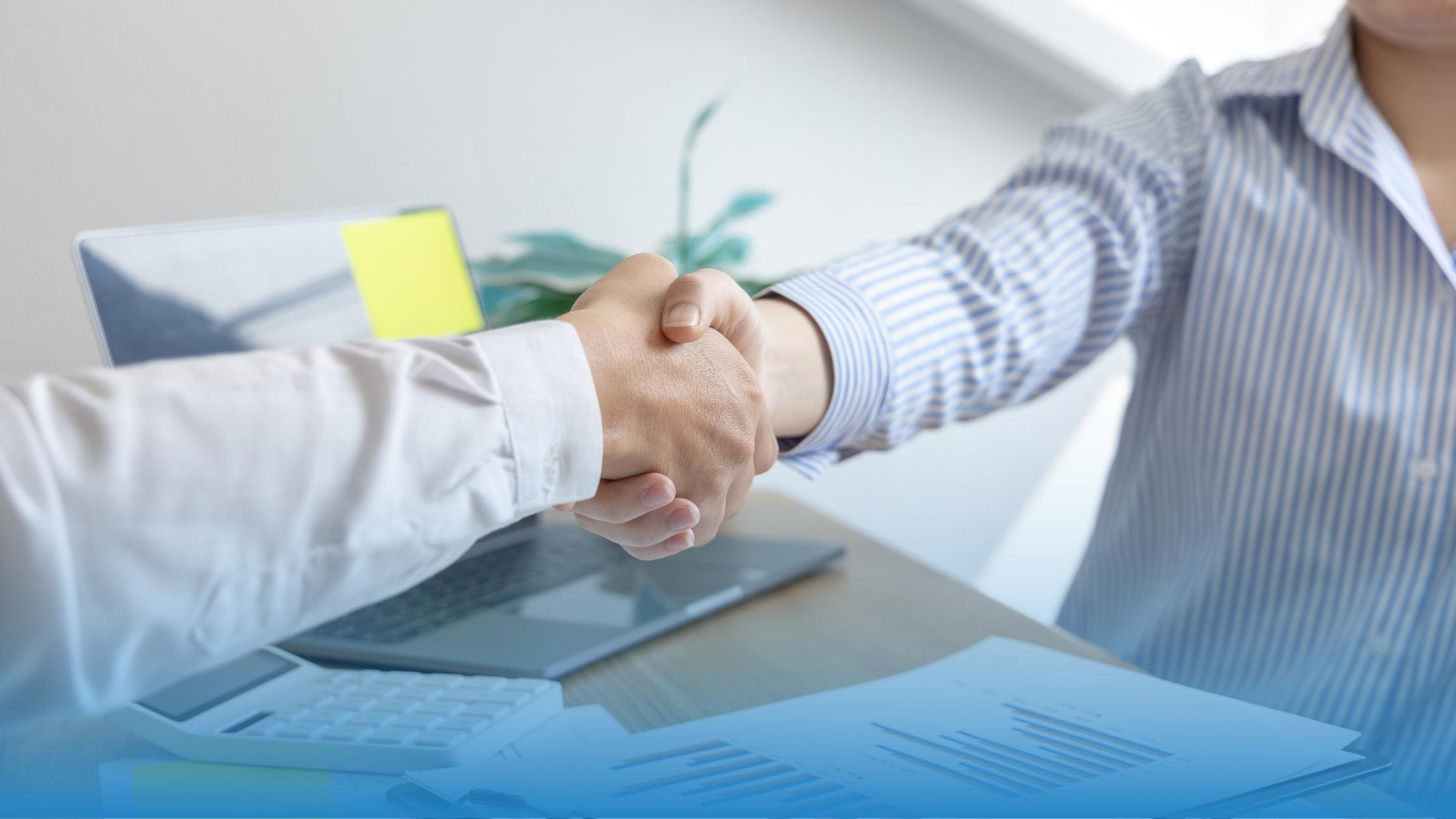 Two professionals shaking hands after reviewing some service agreement metrics together.
