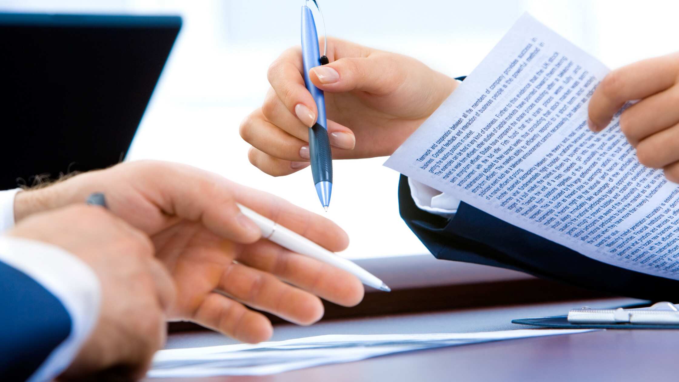Close-up of professionals reviewing and discussing contract language, highlighting negotiation and legal review processes.