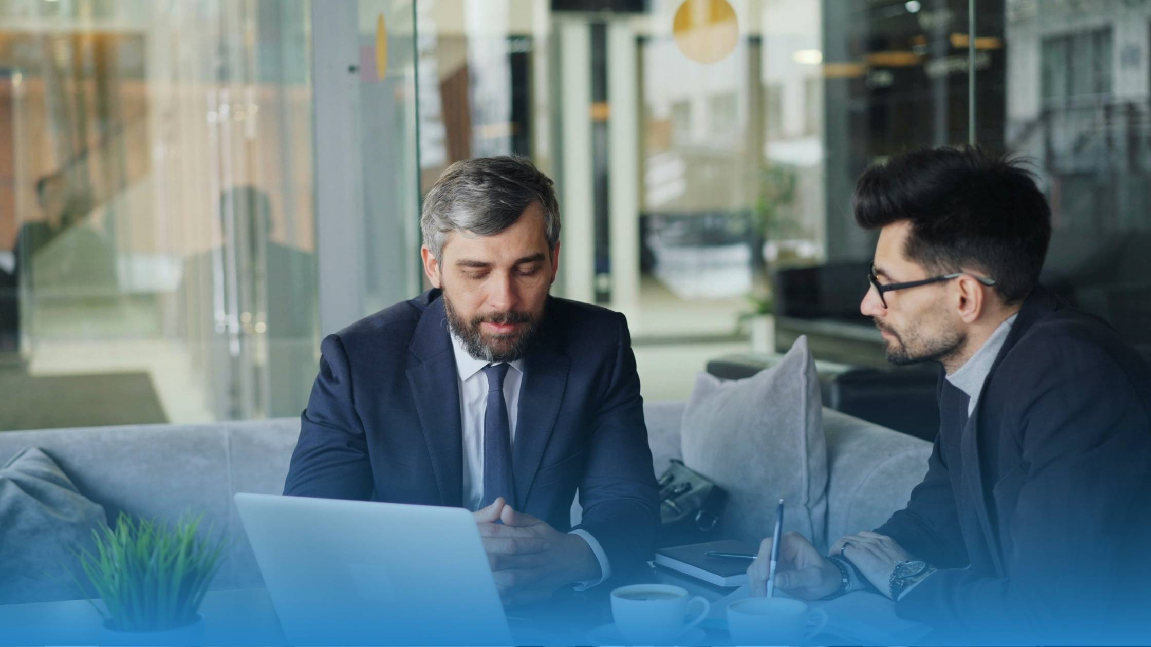 Two in-house legal professionals reviewing contract challenges on a laptop in a modern office setting.