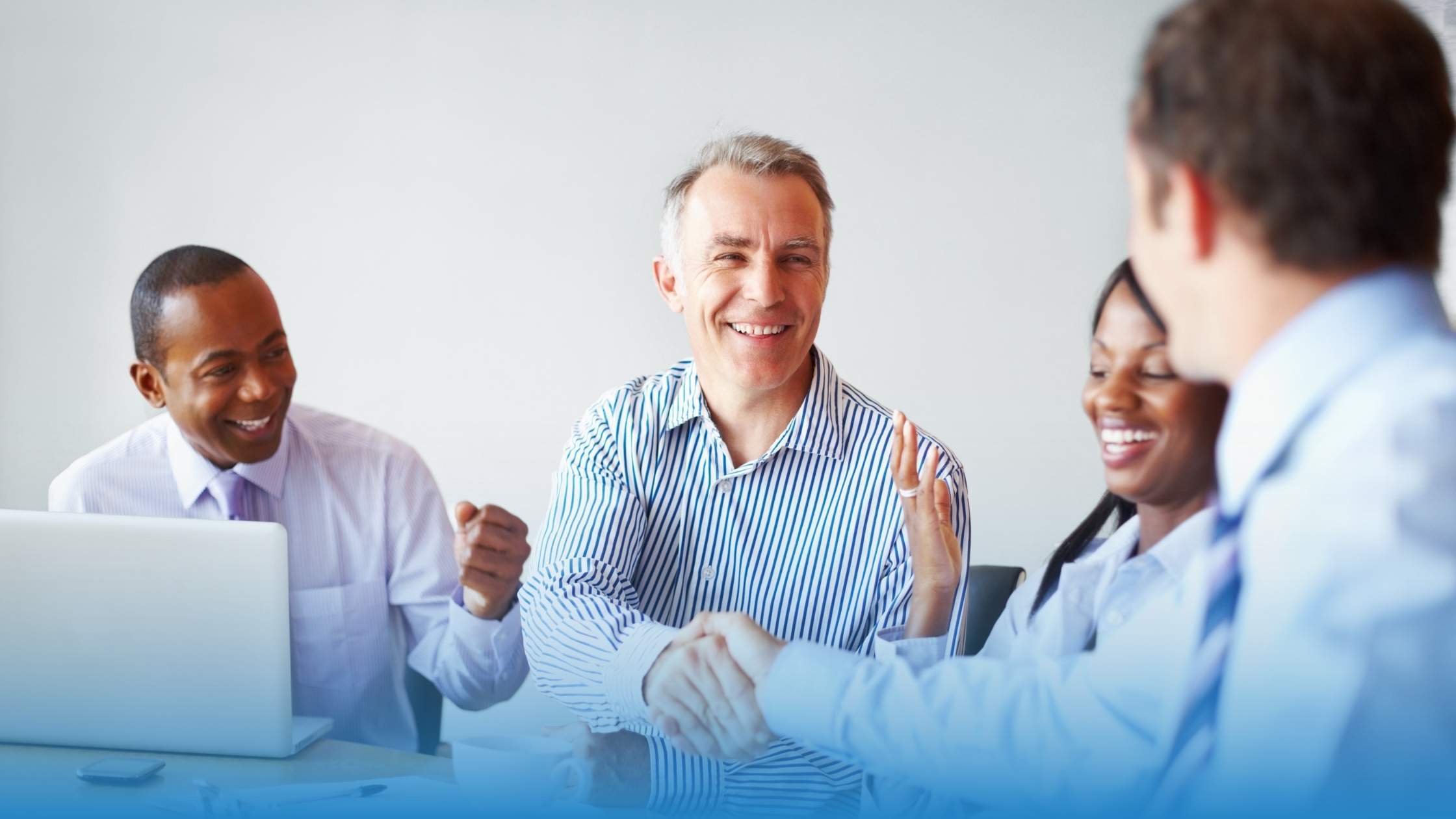 Professionals shaking hands and smiling, symbolizing a successful agreement, with a focus on indemnification