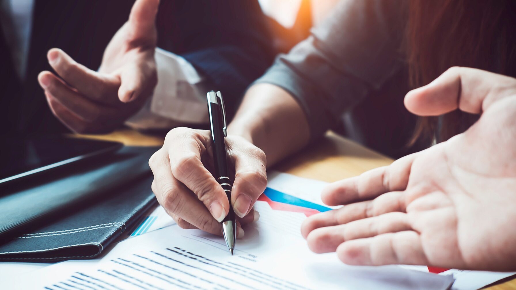 Close-up of professionals reviewing and signing a contract during a business negotiation
